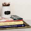 white ceramic pencil organizer on top of stack of books